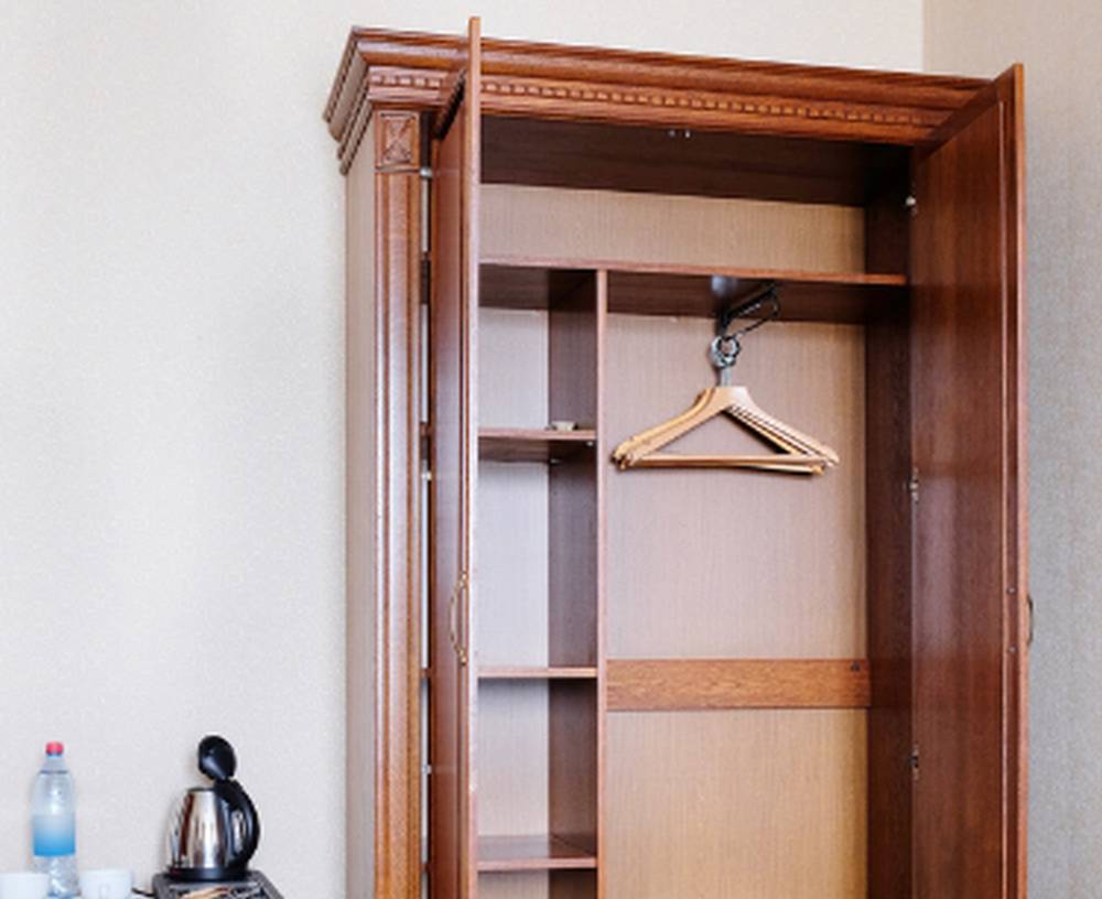 Otwarta szafa z wiszącymi w środku wieszakami